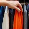 A hand reaching into a rack of clothes, signifying careful selection by a stylist.